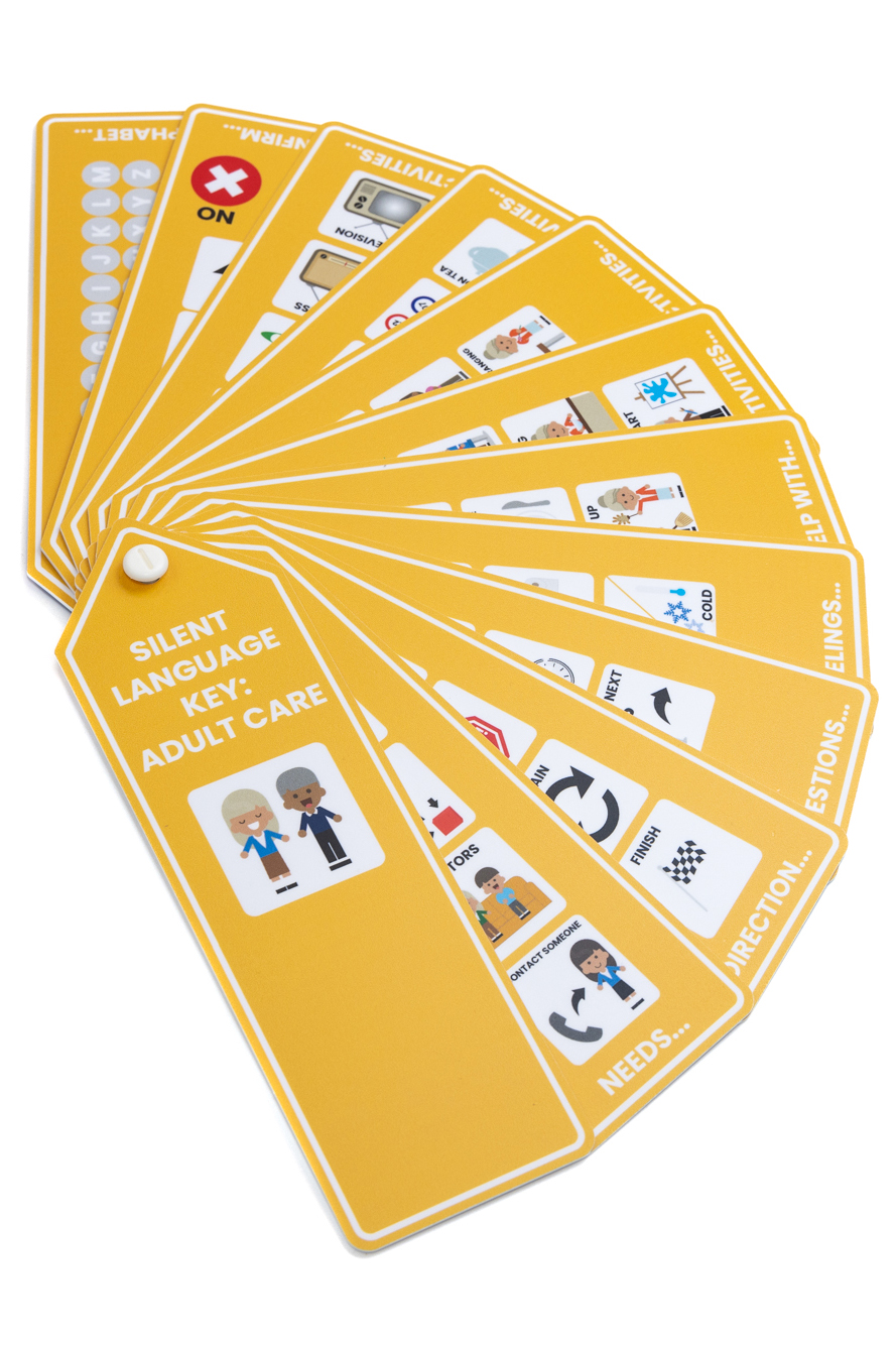 A Voice 4 All Adult Care Silent Language key in orange/yellow the image show the Silent Language Key spread out in a fan with the front cover and individual fans with communication icons visible.